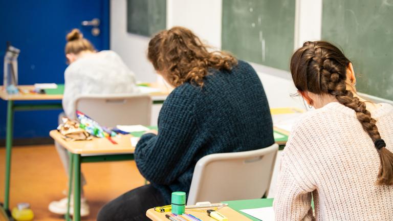 Schülerinnen und Schüler sitzen während der schriftlichen Abiturprüfung in Biologie in einem Klassenzimmer. (Archiv)