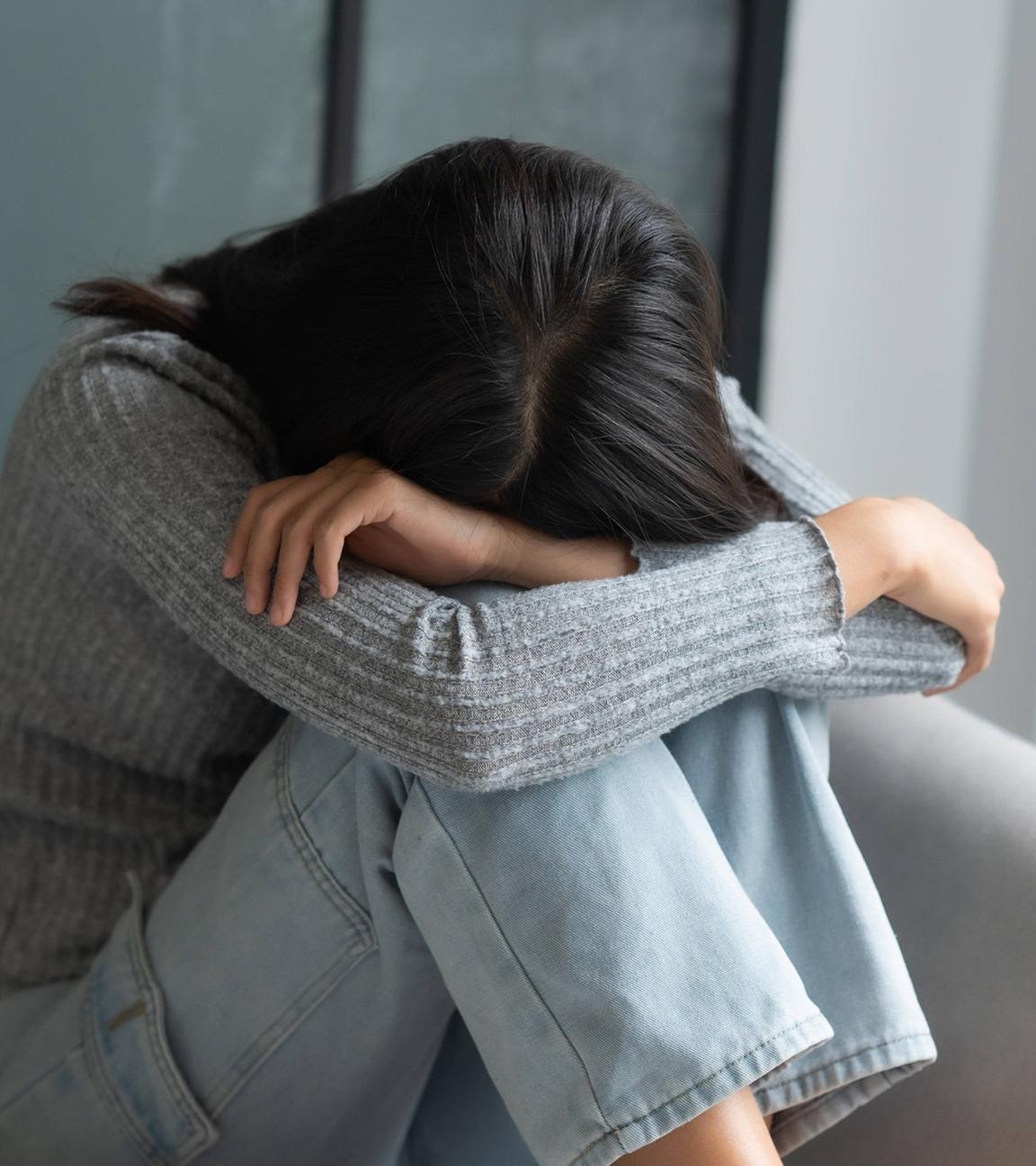 Junge Frau sitzt traurig auf dem Sofa. (Symbolbild)