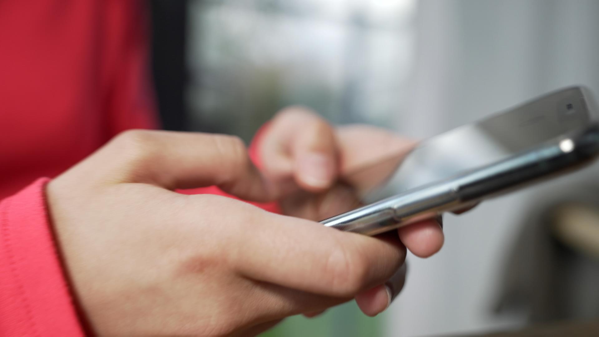 Symbolbild: Hand tippt auf Mobiltelefon