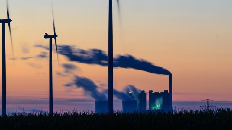 Windräder drehen sich vor der Kulisse des Braunkohlekraftwerkes Schkopau. (Archiv)