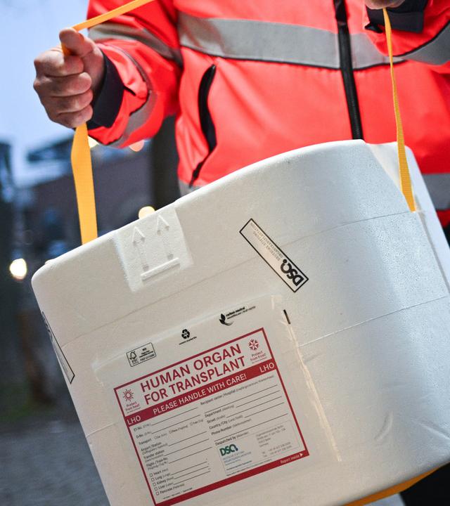  Ein Mitarbeiter der Malteser stellt eine Kühlbox für eine Organspende in einen Transporter. (Gestellte Szene)