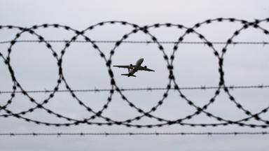 Ein Flugzeug startet - fotografiert durch Stacheldraht am Flughafenzaun. (Symbolbild)