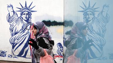 Ältere Frau geht am 28. Januar 2026 in Teheran an einem anti‑amerikanischen Wandbild vorbei