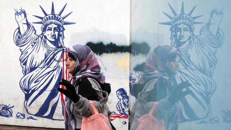 Ältere Frau geht am 28. Januar 2026 in Teheran an einem anti‑amerikanischen Wandbild vorbei