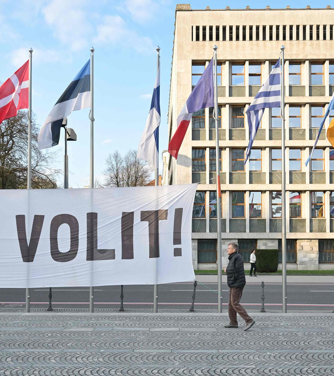 Banner mit der Aufschrift „Let’s vote“ vor dem Parlament in Ljubljana, Slowenien, während Demonstrierende bei einer Kundgebung zur Teilnahme an den Parlamentswahlen aufrufen.