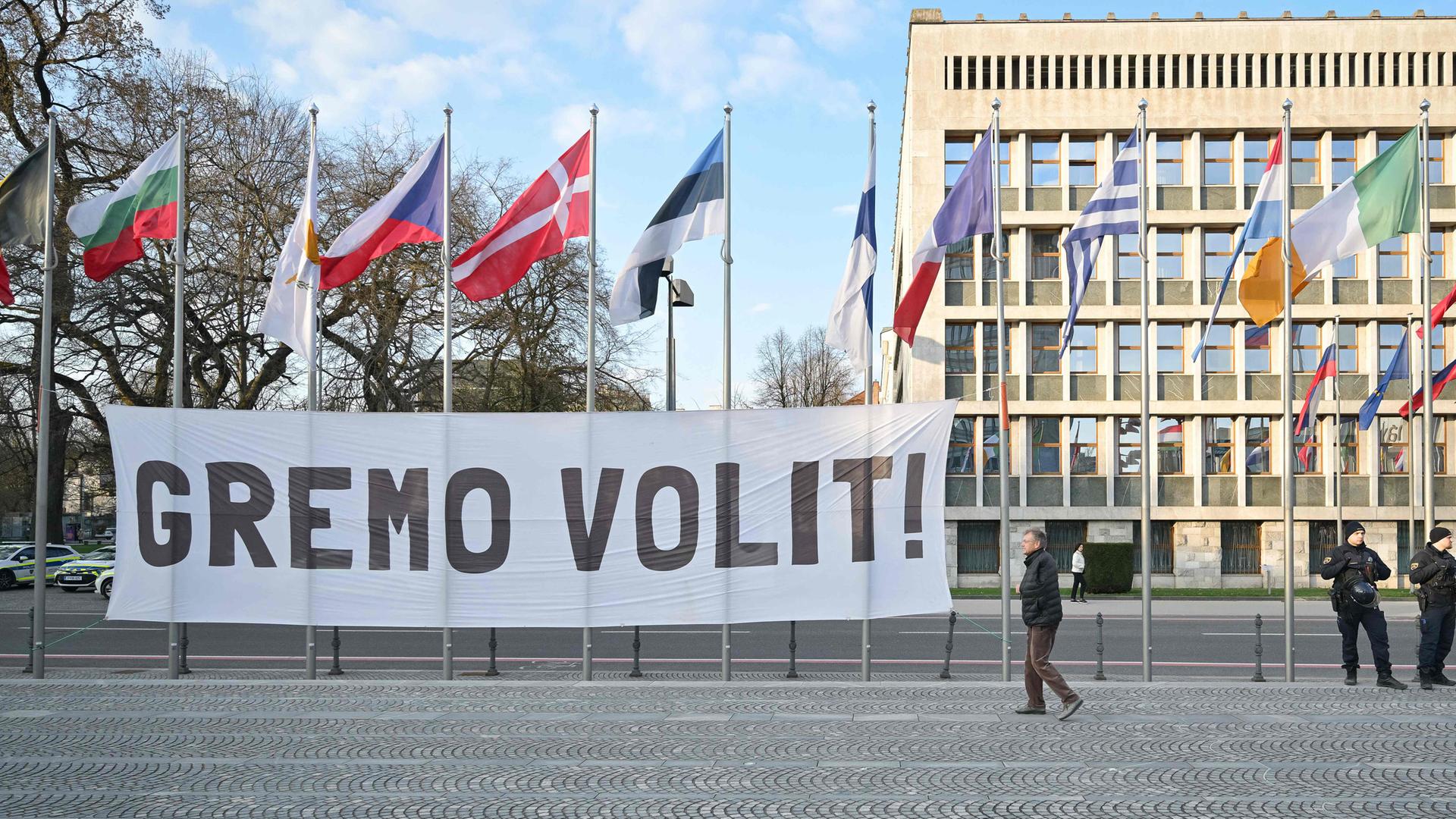 Banner mit der Aufschrift „Let’s vote“ vor dem Parlament in Ljubljana, Slowenien, während Demonstrierende bei einer Kundgebung zur Teilnahme an den Parlamentswahlen aufrufen.