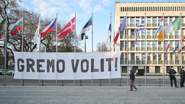 Banner mit der Aufschrift „Let’s vote“ vor dem Parlament in Ljubljana, Slowenien, während Demonstrierende bei einer Kundgebung zur Teilnahme an den Parlamentswahlen aufrufen.