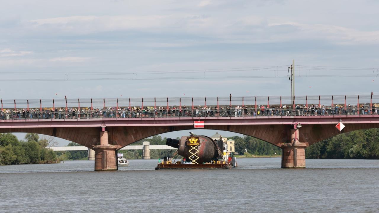 Das U-Boot fährt auf die Seite gedreht unter einer tiefen Brücke hindurch