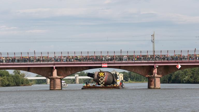 Das U-Boot fährt auf die Seite gedreht unter einer tiefen Brücke hindurch