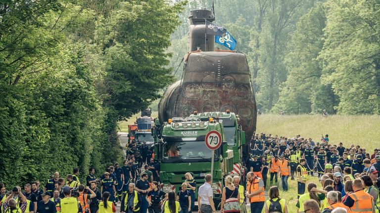 Das U-Boot wird auf einem Lkw transportiert, umringt von vielen Menschen