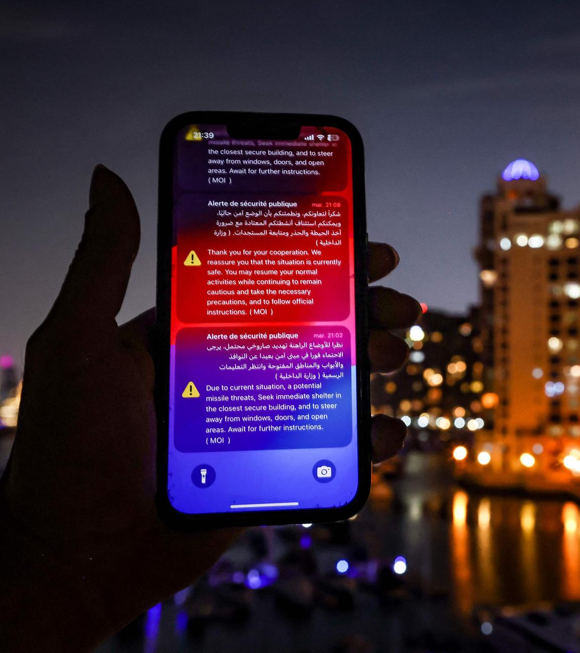 Auf einem Smartphone sind im Dunkeln Warnungen vor iranischen Luftangiffen in Dubai zu sehen.