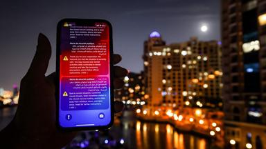 Auf einem Smartphone sind im Dunkeln Warnungen vor iranischen Luftangiffen in Dubai zu sehen.