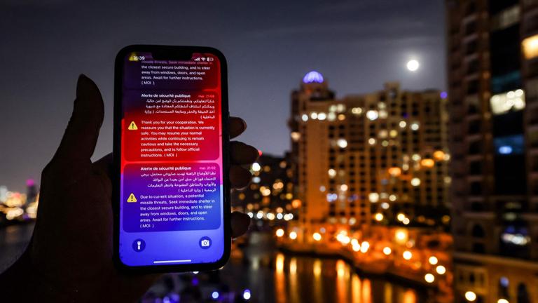 Auf einem Smartphone sind im Dunkeln Warnungen vor iranischen Luftangiffen in Dubai zu sehen.