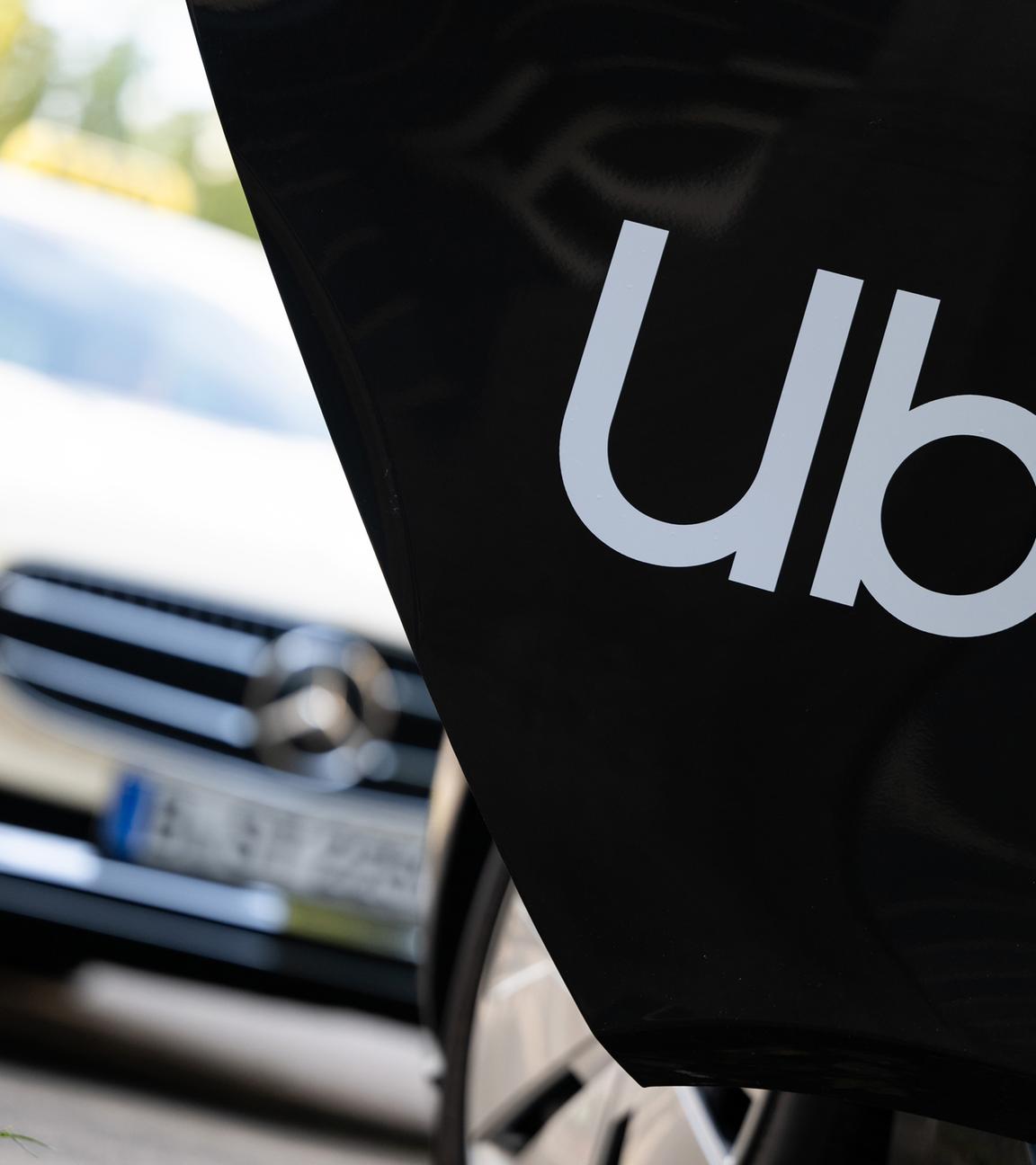 Berlin: Ein Mietwagen mit einem Schriftzug des Mobilitätsdienstleisters und Fahrtenvermittlers Uber steht vor einem Taxi, das auch über das Unternehmen gebucht werden kann.