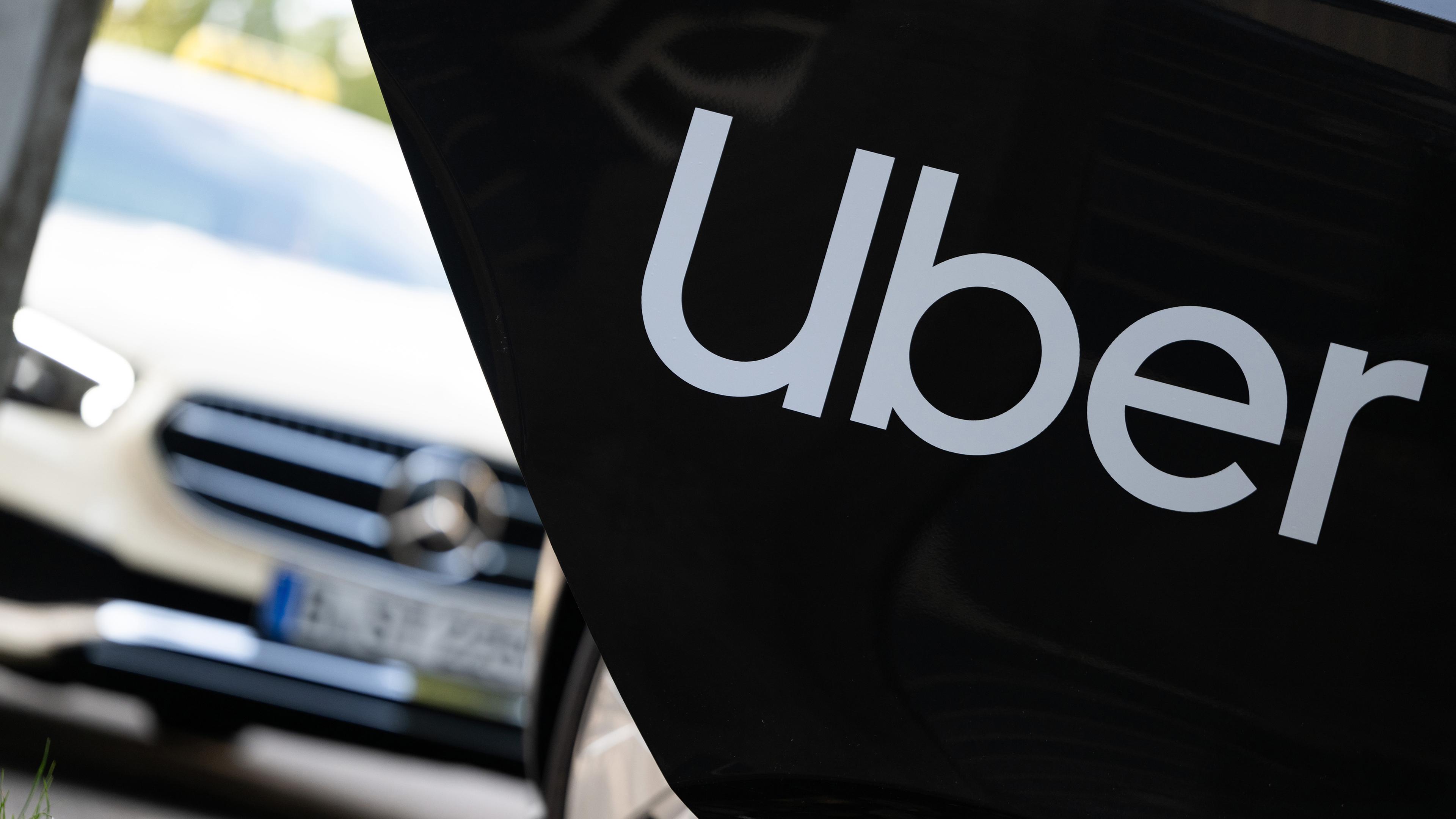Berlin: Ein Mietwagen mit einem Schriftzug des Mobilitätsdienstleisters und Fahrtenvermittlers Uber steht vor einem Taxi, das auch über das Unternehmen gebucht werden kann.