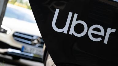 Berlin: Ein Mietwagen mit einem Schriftzug des Mobilitätsdienstleisters und Fahrtenvermittlers Uber steht vor einem Taxi, das auch über das Unternehmen gebucht werden kann.