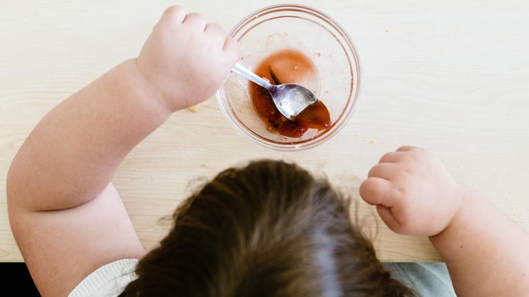 Ein dickes Mädchen stochert  in seiner Nachspeise herum. 