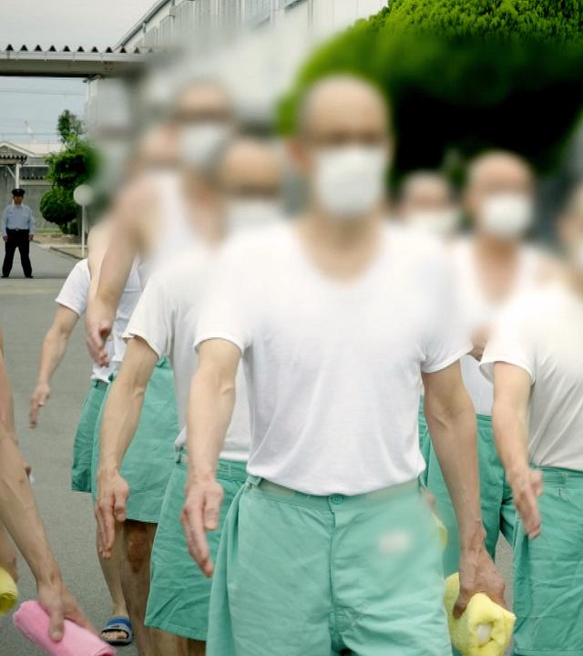 Inhaftierte der Strafvollzugsanstalt Osaka marschieren im Gleichschritt über den Hof. Ihre Gesichter sind unkenntlich gemacht.