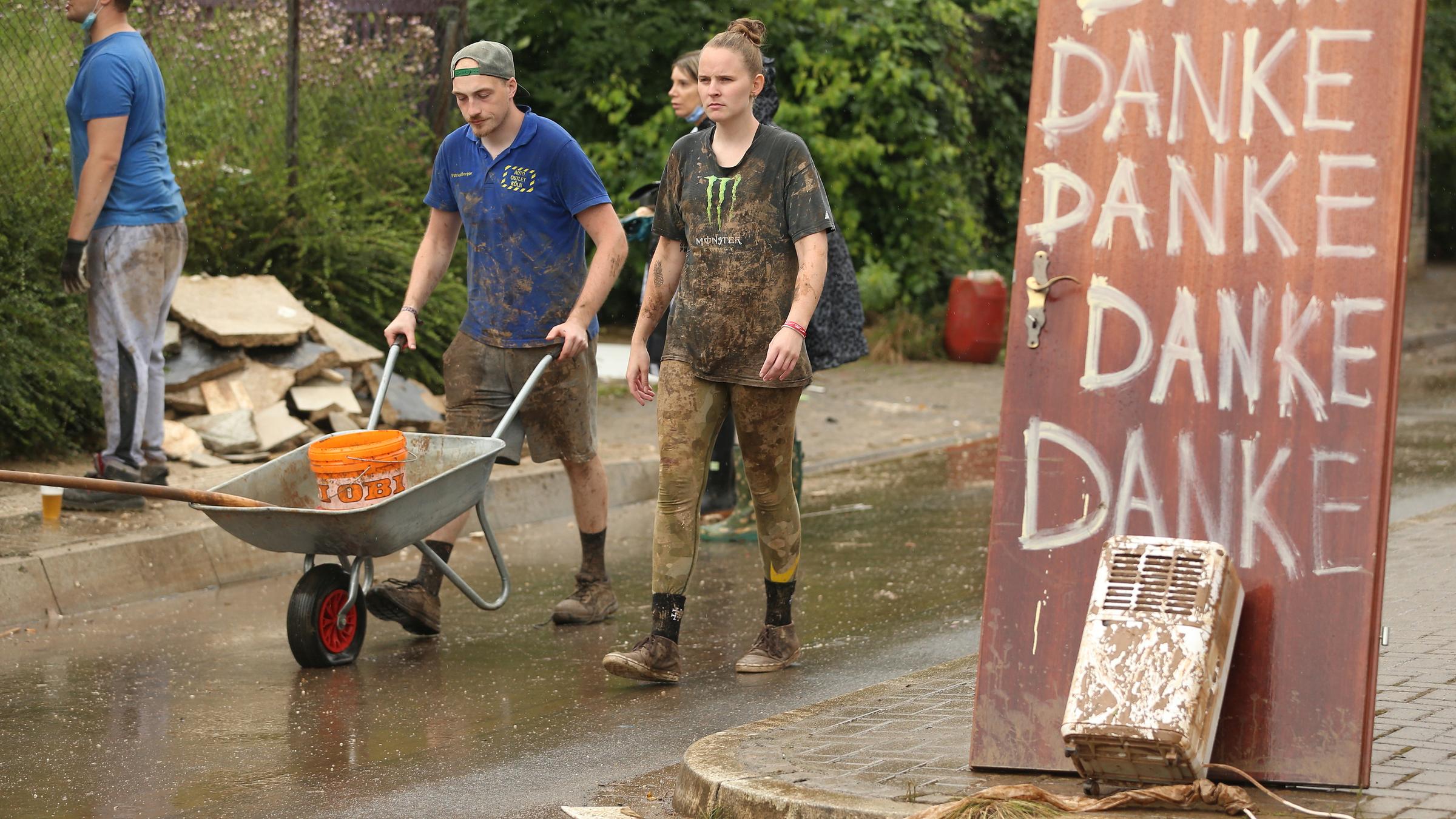 Zwei Leute, ein Mann und eine Frau schieben eine Schubkarre.