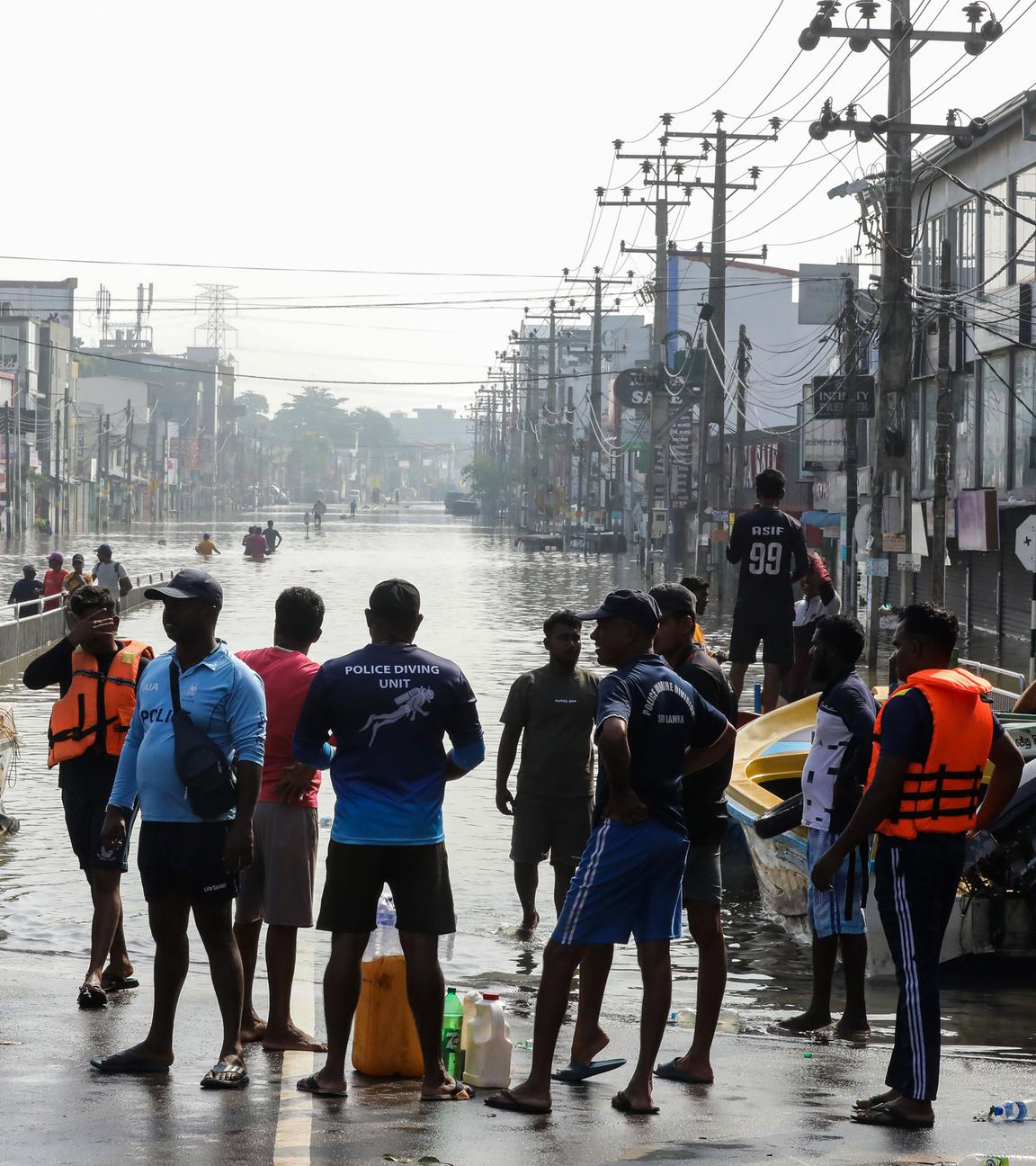 Menschen stehen vor einer überfluteten Straße in Sri Lanka
