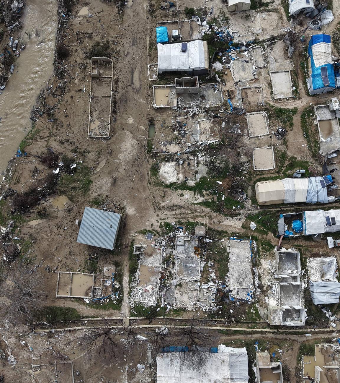Eine Luftaufnahme zeigt beschädigte und überflutete Zelte und Notunterkünfte, während sich die Bewohner inmitten der Trümmer versammeln, nachdem starke Regenfälle am 06.02.2026 die Flüchtlingslager in der Region Hirbet al-Jawz in Idlib, Syrien, überschwemmt haben. 