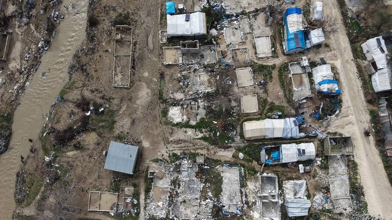 Eine Luftaufnahme zeigt beschädigte und überflutete Zelte und Notunterkünfte, während sich die Bewohner inmitten der Trümmer versammeln, nachdem starke Regenfälle am 06.02.2026 die Flüchtlingslager in der Region Hirbet al-Jawz in Idlib, Syrien, überschwemmt haben. 