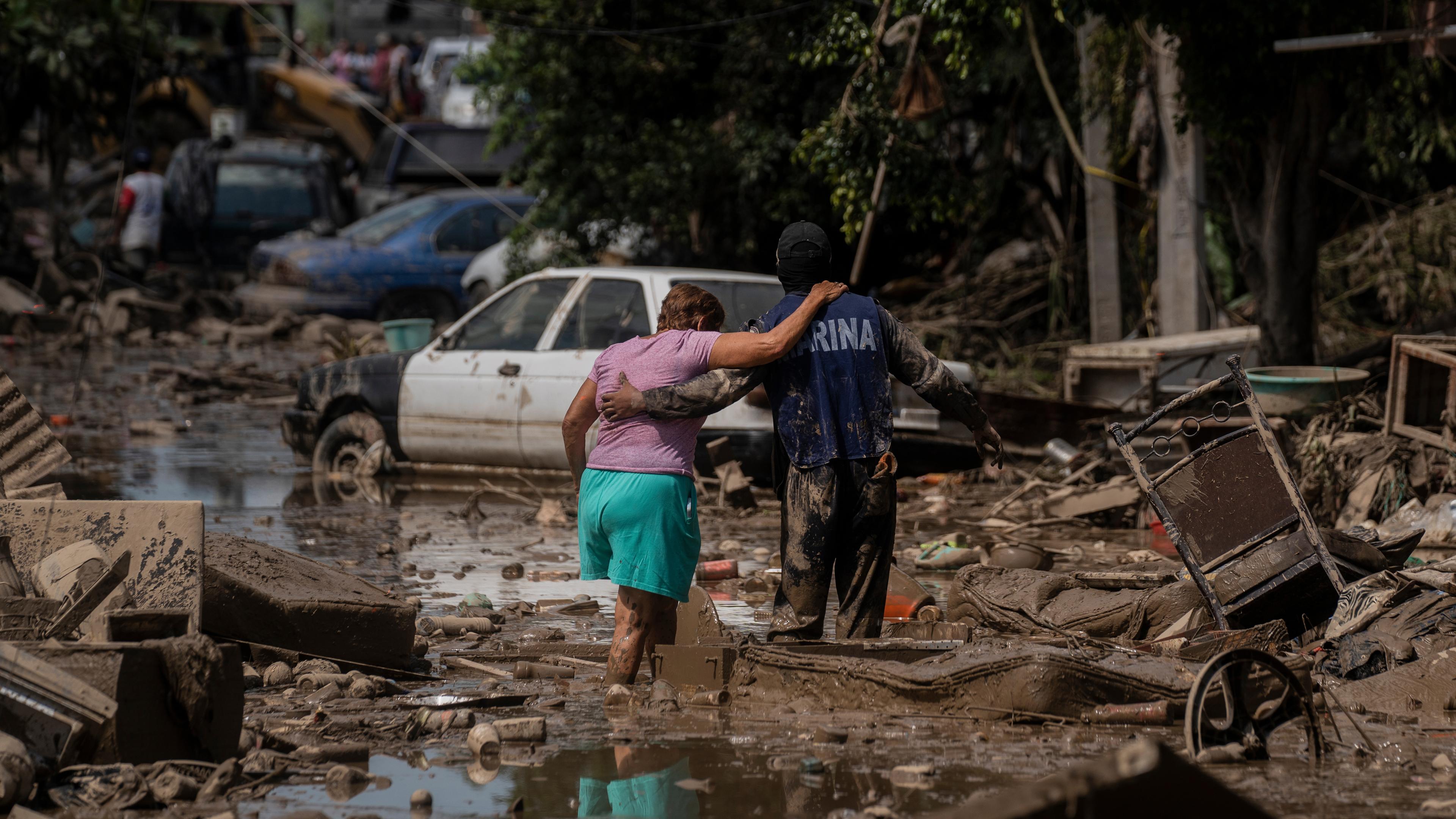 Ein Marine hilft einer Frau am Sonntag, dem 12.10.2025, in Poza Rica im mexikanischen Bundesstaat Veracruz, eine überflutete Straße zu überqueren. 