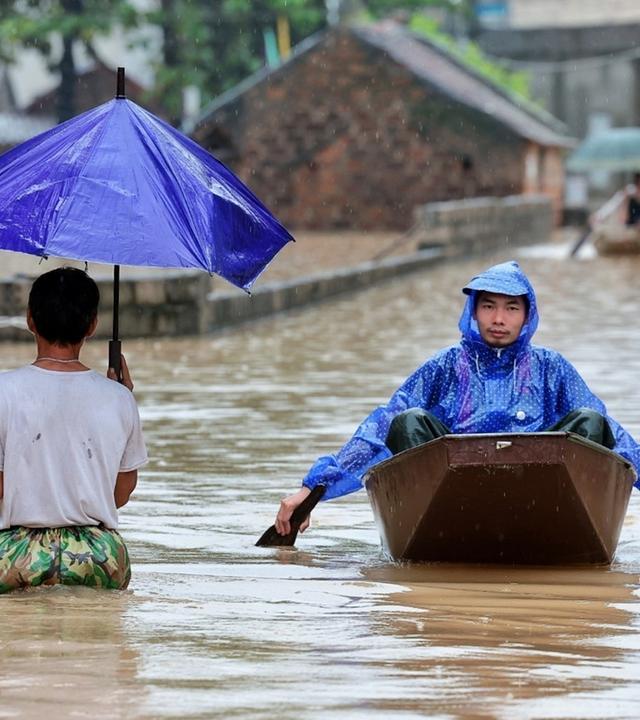 Anwohner pendeln mit Booten durch ein überflutetes Dorf am Stadtrand von Hanoi, Vietnam. 