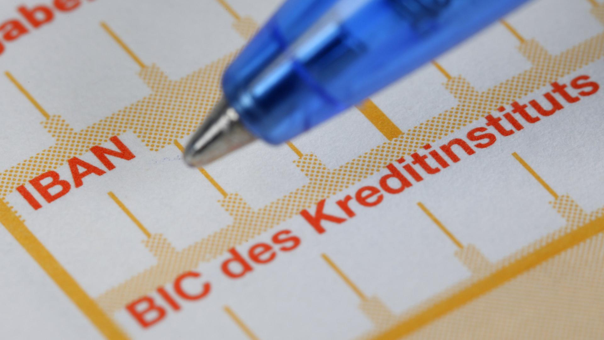Ein Kugelschreiber liegt neben einem Überweisungsträger mit den Schriftzügen IBAN und BIC.