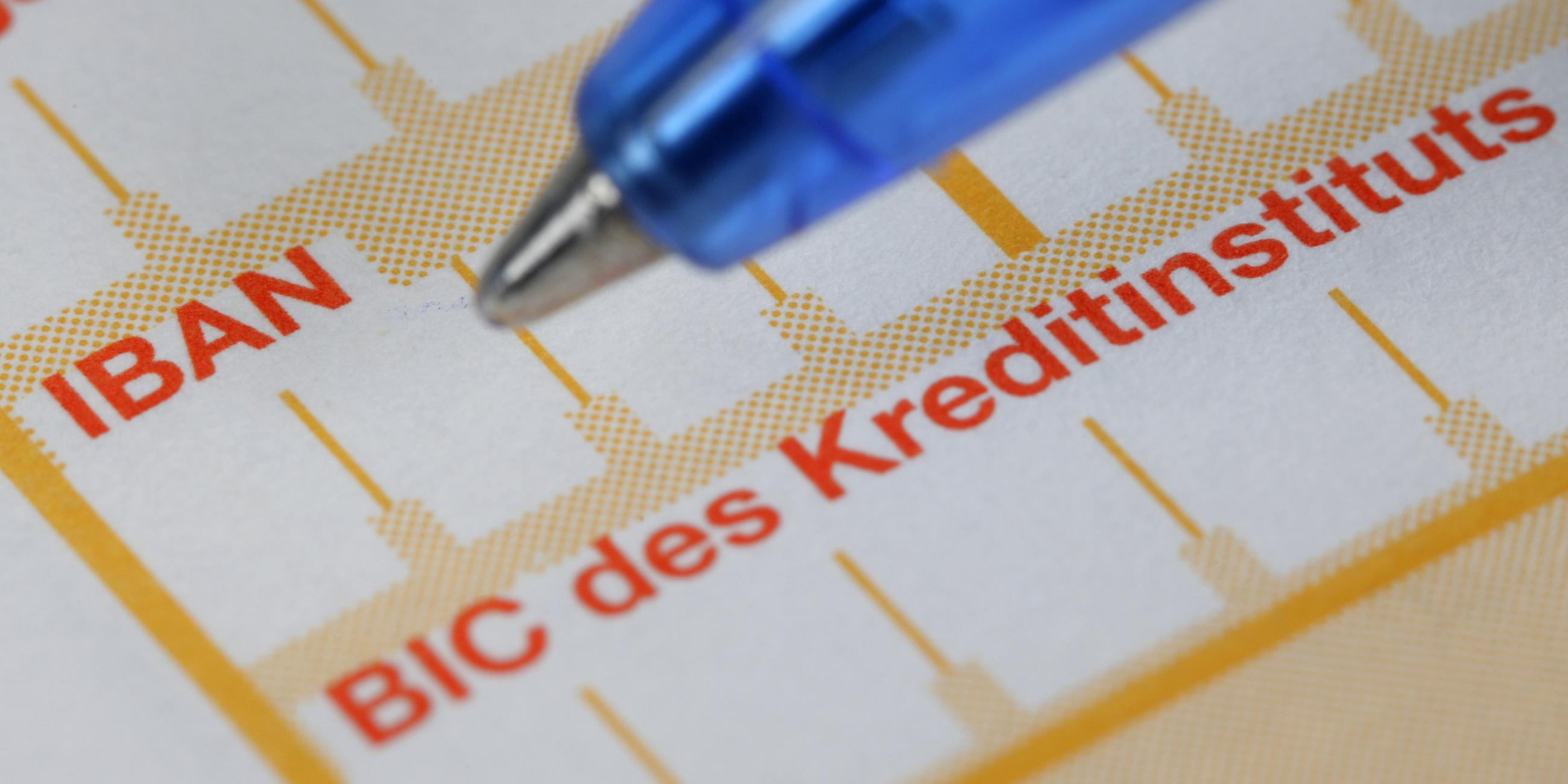 Ein Kugelschreiber liegt neben einem Überweisungsträger mit den Schriftzügen IBAN und BIC.