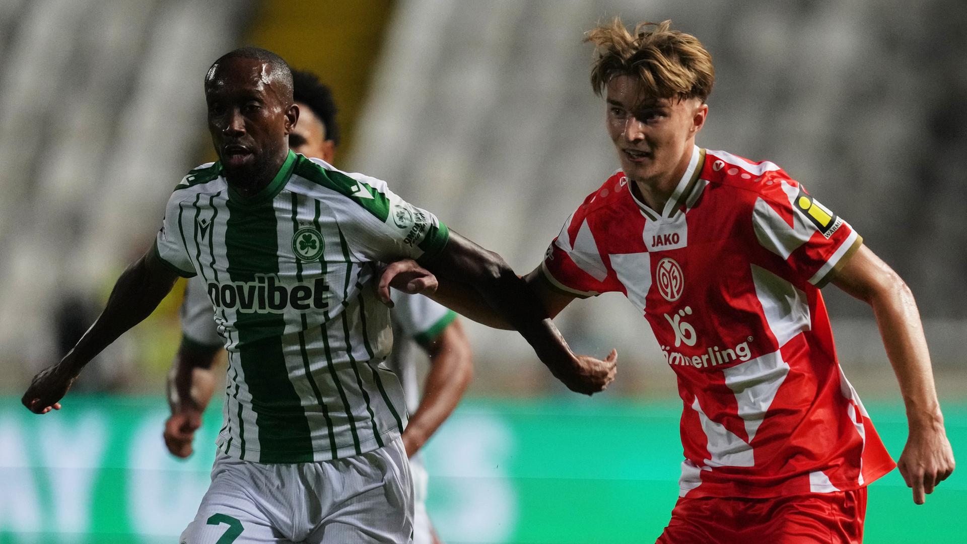02.10.2025, Nikosia: Willy Semedo (l.) von Omonia wird im Conference-League-Spiel gegen Mainz 05 von Kacper Potulski unter Druck gesetzt.