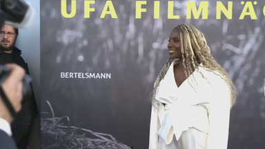 Das Bild zeigt Model Nikeata Thompson in einem weißen Mantel, die von Reportern fotografiert wird.