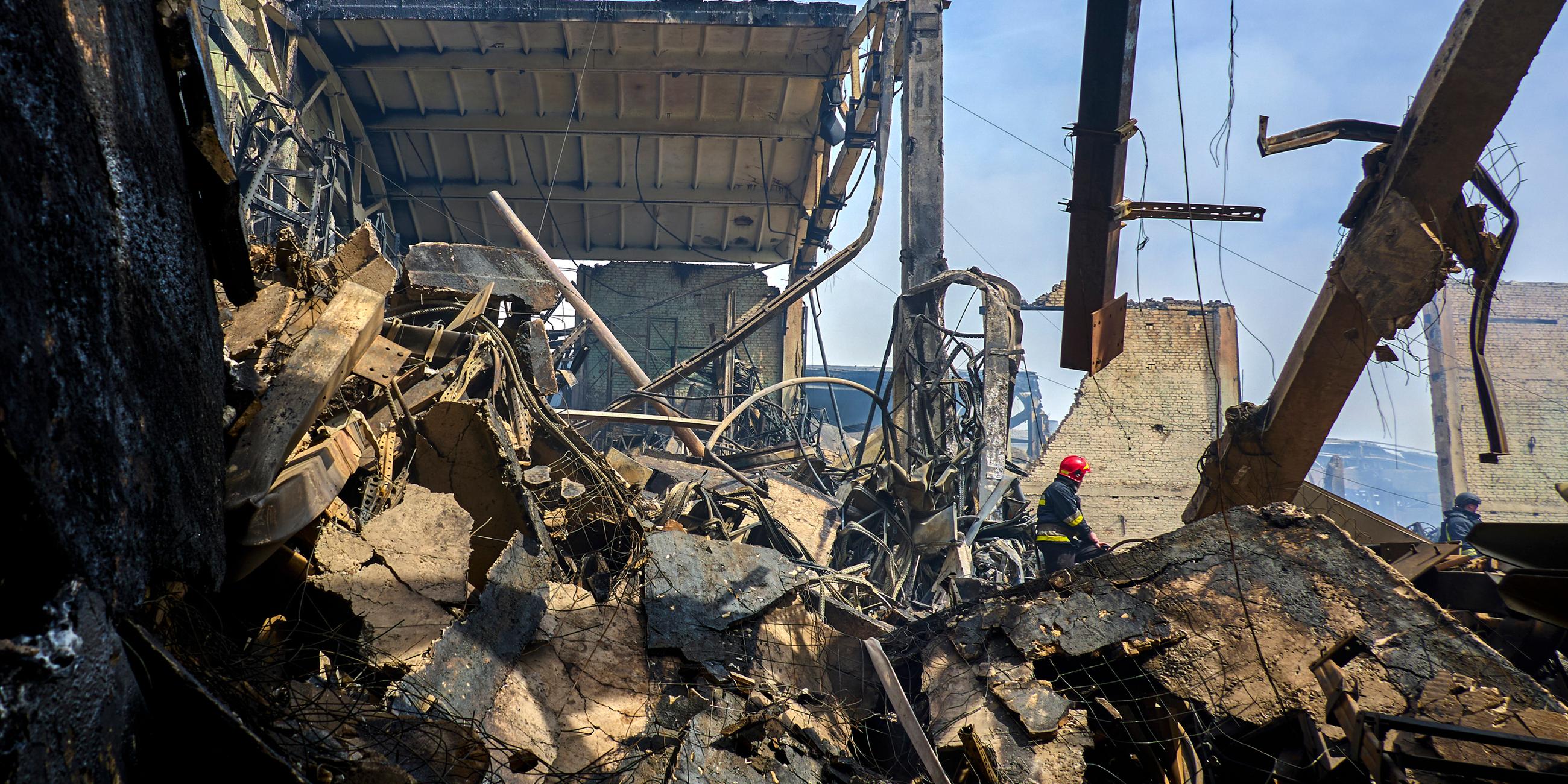 Ukrainische Feuerwehrleute und Rettungskräfte arbeiten an der Stelle eines beschädigten Lagers einer privaten Fabrik nach einem nächtlichen Angriff in Wasyschtschewe, Ukraine.