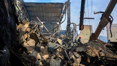 Ukrainische Feuerwehrleute und Rettungskräfte arbeiten an der Stelle eines beschädigten Lagers einer privaten Fabrik nach einem nächtlichen Angriff in Wasyschtschewe, Ukraine.