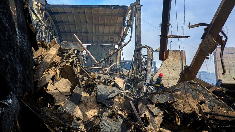 Ukrainische Feuerwehrleute und Rettungskräfte arbeiten an der Stelle eines beschädigten Lagers einer privaten Fabrik nach einem nächtlichen Angriff in Wasyschtschewe, Ukraine.