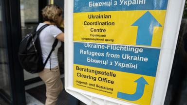 Besucher gehen an einem Hinweisschild der Initiative Ukrainian Coordination Center (UCC) am Eingang zum Amt für multikulturelle Angelegenheiten der Stadt Frankfurt am Main vorbei.