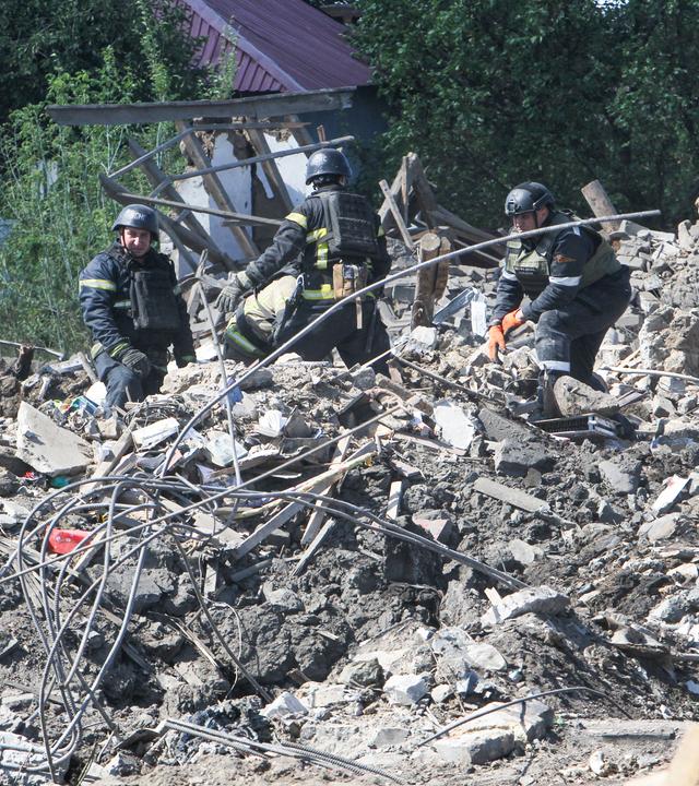 Ukrainische Rettungskräfte suchen unter den Trümmern eines eingestürzten Wohnhauses nach Überlebenden.