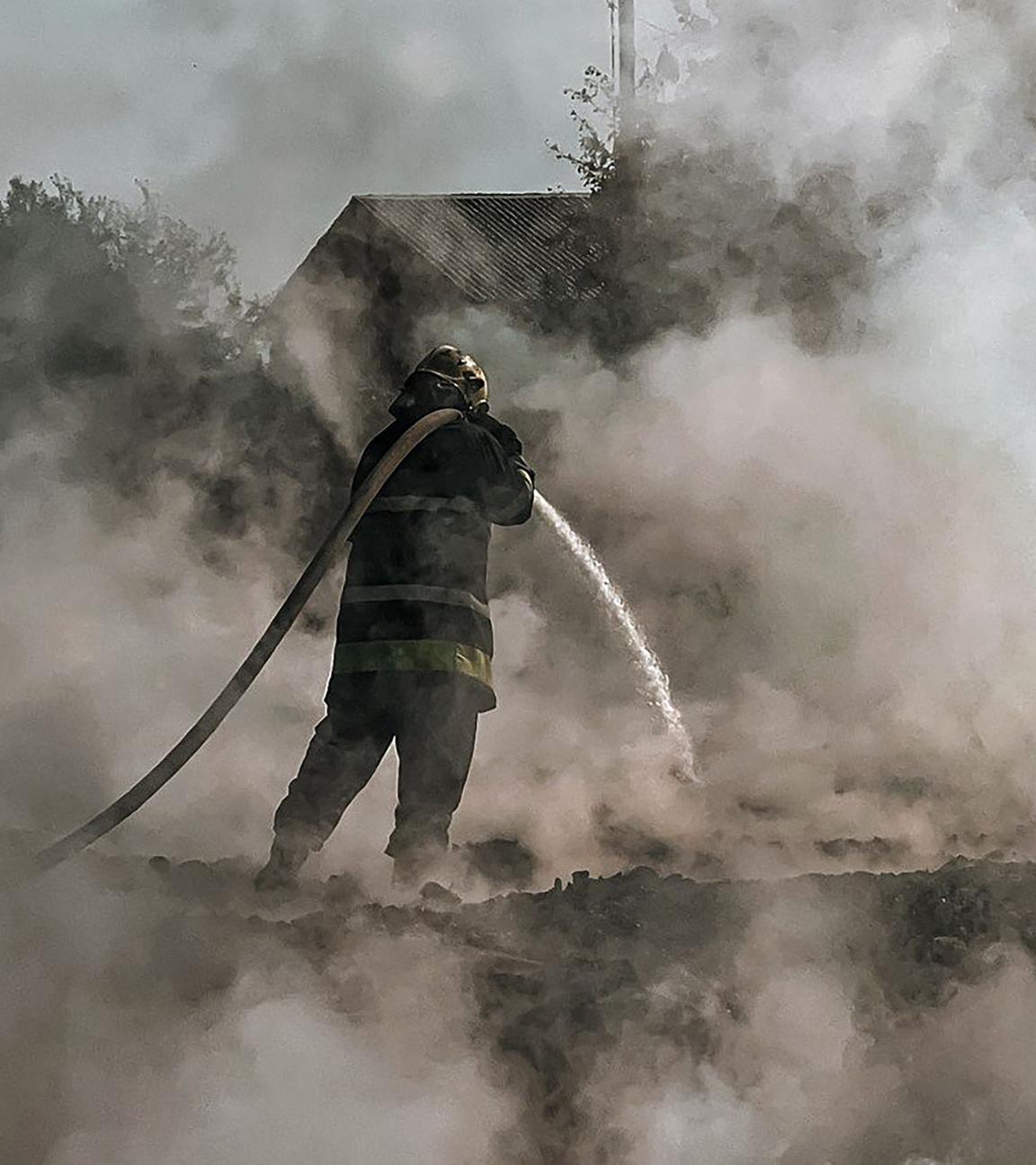 It shows a firefighter extinguishing a fire after a Russian attack in Kyiv region.