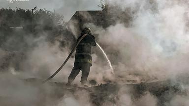 It shows a firefighter extinguishing a fire after a Russian attack in Kyiv region.