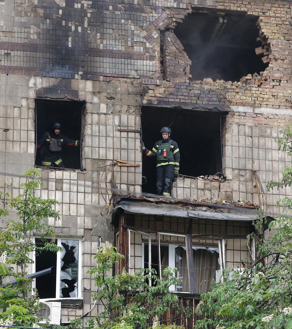 Ukrainische Einsatzkräfte stehen in einem beschädigten Gebäude in Kiew nach einem russischen Angriff.