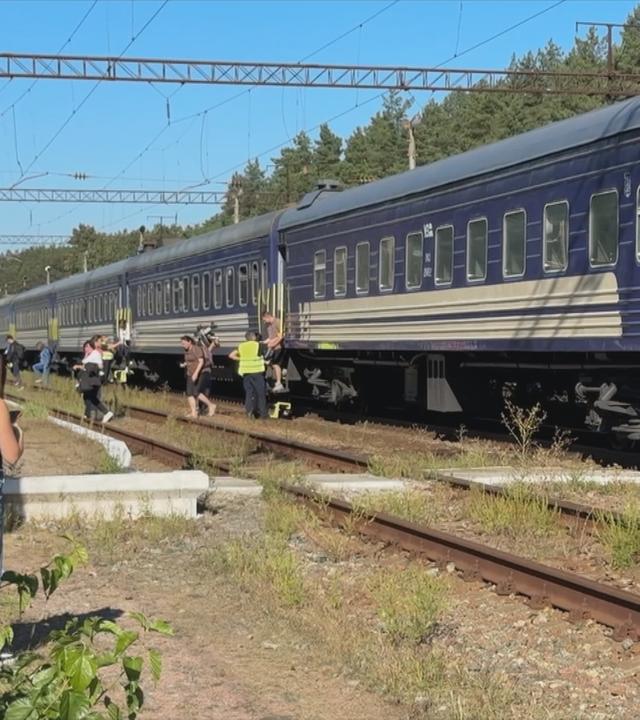 Menschen stehen vor einem Zug, der evakuiert werden musste.