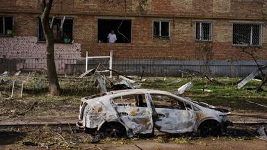 Ein Mann blickt am frühen Dienstag nach einem russischen Raketen- und Drohnenangriff in Kiew, Ukraine, aus seiner Wohnung. Das Wohnhaus und ein Auto sind stark beschädigt.