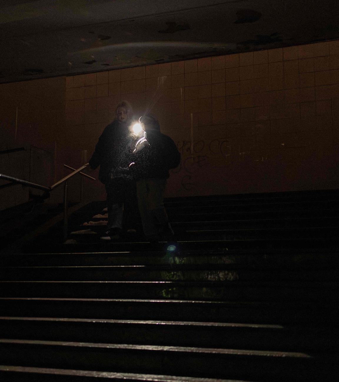 Menschen gehen mit Taschenlampe durch einen dunklen Untergrundgang in Kiew während eines Stromausfalls.