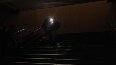 Menschen gehen mit Taschenlampe durch einen dunklen Untergrundgang in Kiew während eines Stromausfalls.