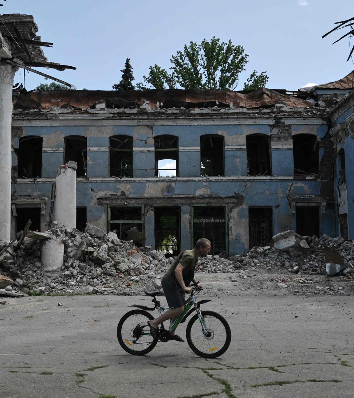 Ein Mann fährt mit dem Fahrrad an einem zerstörten Gebäude in Druzhkivka, Region Donezk, vorbei – aufgenommen am 15. August 2025.