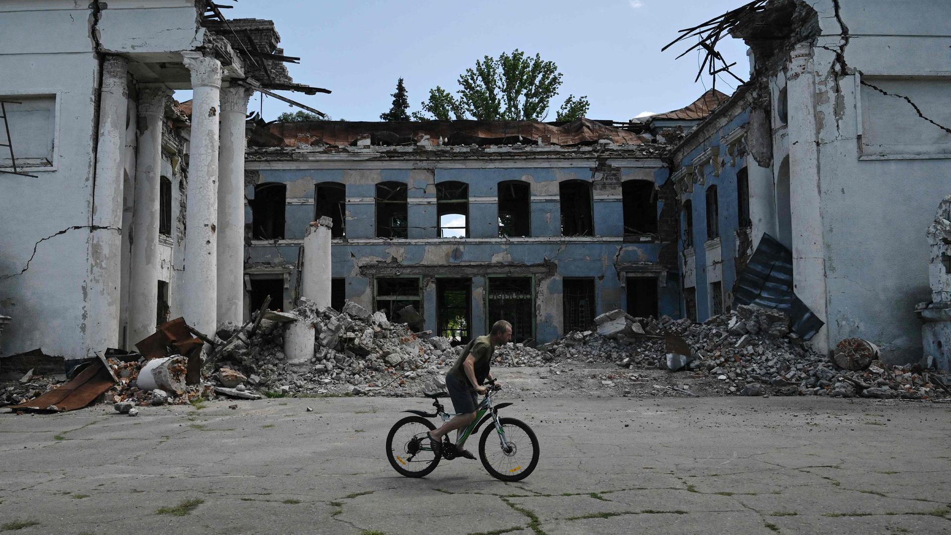 Ein Mann fährt mit dem Fahrrad an einem zerstörten Gebäude in Druzhkivka, Region Donezk, vorbei – aufgenommen am 15. August 2025.