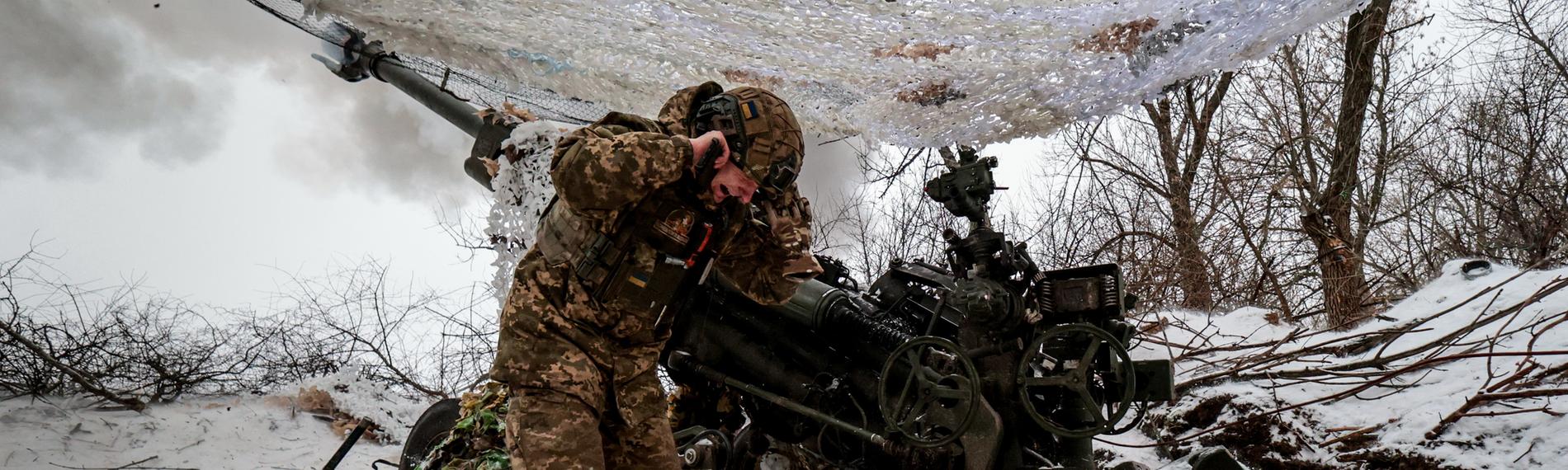 Ein Soldat hält sich vor Kriegsgerät die Ohren zu.