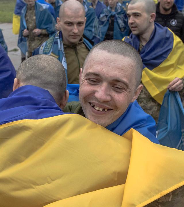 Freigelassene ukrainische Kriegsgefangene umarmen sich nach einem Gefangenenaustausch an einem nicht genannten Ort in der Region Tschernihiw am 15. Mai 2026.