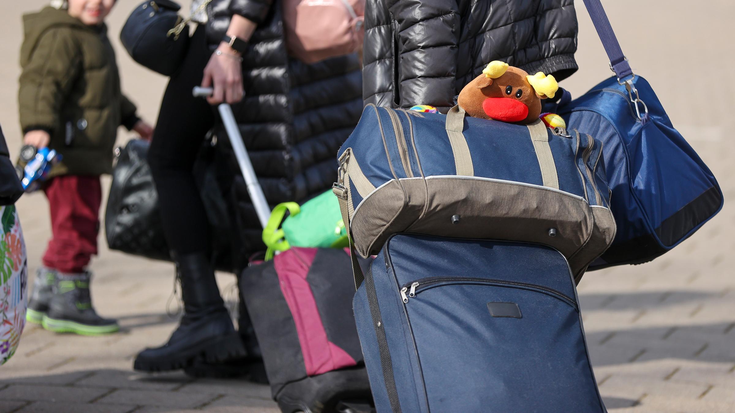 Ukrainische Flüchtlinge gehen mit ihrem Gepäck in eine Erstaufnahmeeinrichtung.