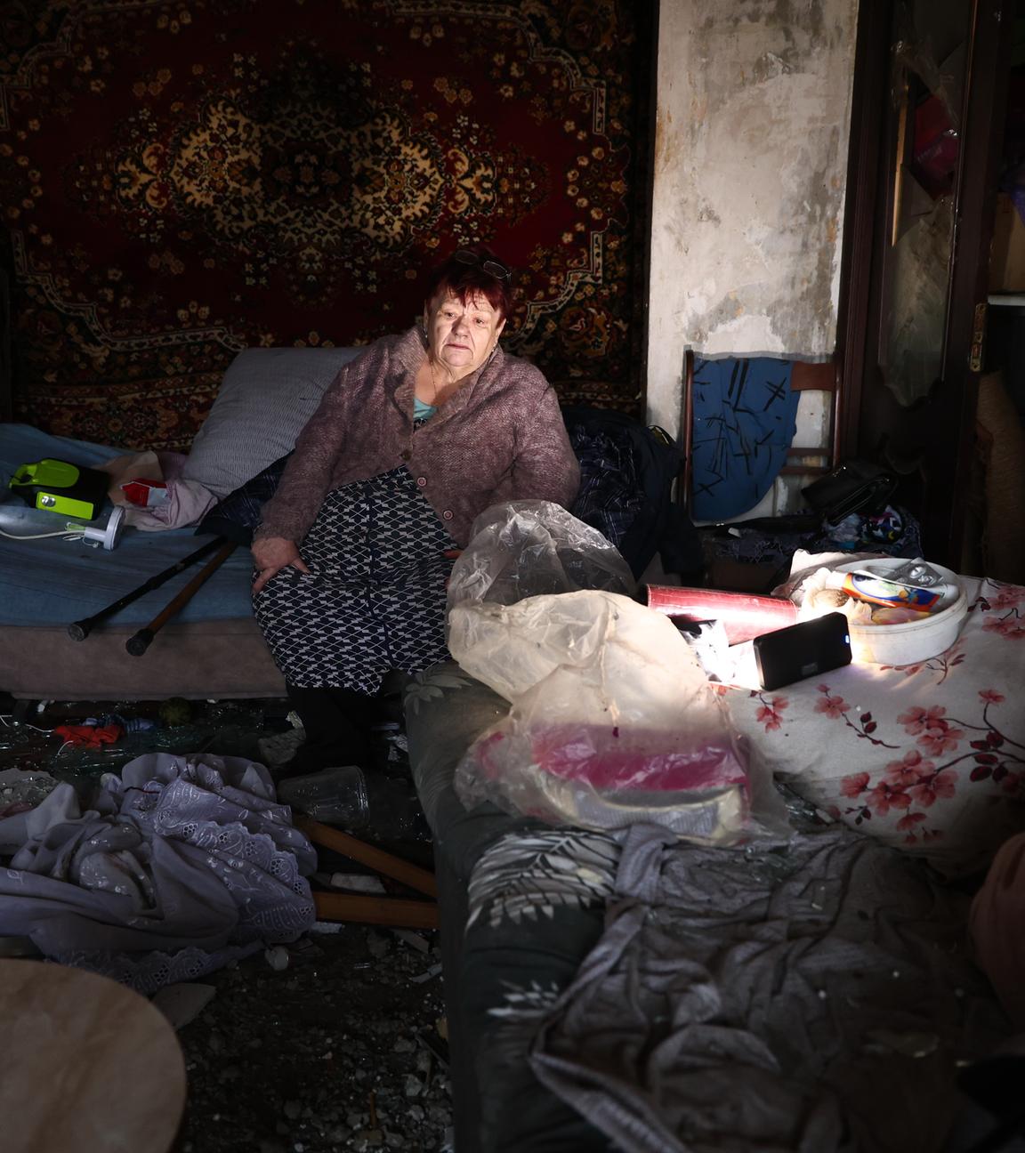 Eine ältere Frau sitzt in ihrer beschädigten Wohnung, nachdem eine russische Drohne das Wohnhaus getroffen hat.